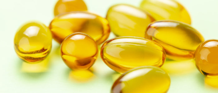 Close up of Vitamin D3 Omega 3 fish oil capsules on green background