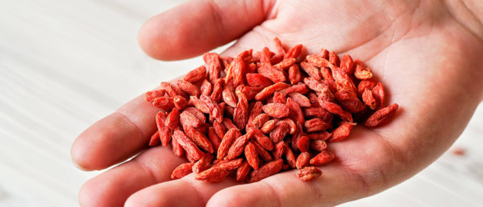 Young,Man,Hand,With,Dried,Goji,Berries,Over,White,Boards